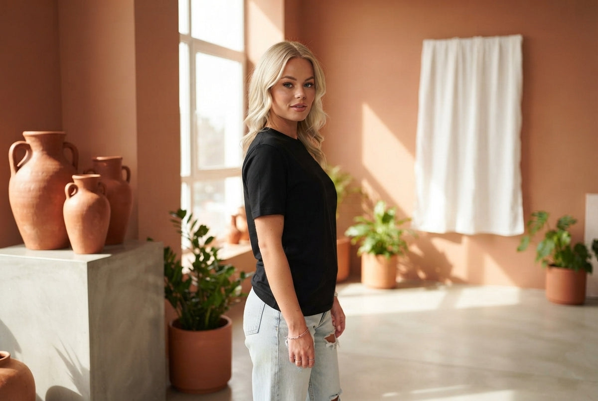 A person wearing a high-quality fitted t-shirt standing in a sunlit room with terracotta and burnt sienna decor.